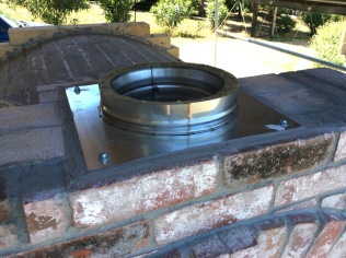 Chimney flue collar installed using thin-set mortar and expansion bolts set into brick.